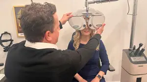 A man is adjusting a machine on a woman's head in a room