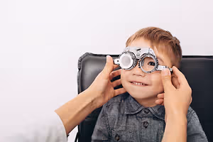A child with glasses on his eyes is being checked by a doctor in a clinic.