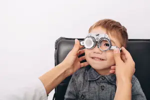 A child with glasses on his eyes is being checked by a doctor in a clinic.