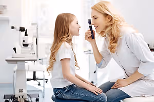 A woman doctor examining a young girl's eye in an eye clinic