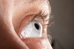 A close up of a woman's eye with eyelashes and a slight reflection of light