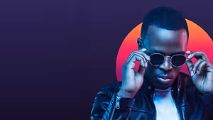 A man adjusting his sunglasses and posing for a photo with a colorful background