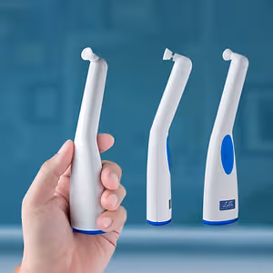 A hand holding a white and blue toothbrush with three toothbrushes in the background