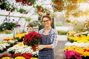 A woman in a greenhouse holding a plant in a pot