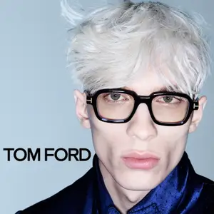 A person with white hair wearing Tom Ford glasses and a blue shirt