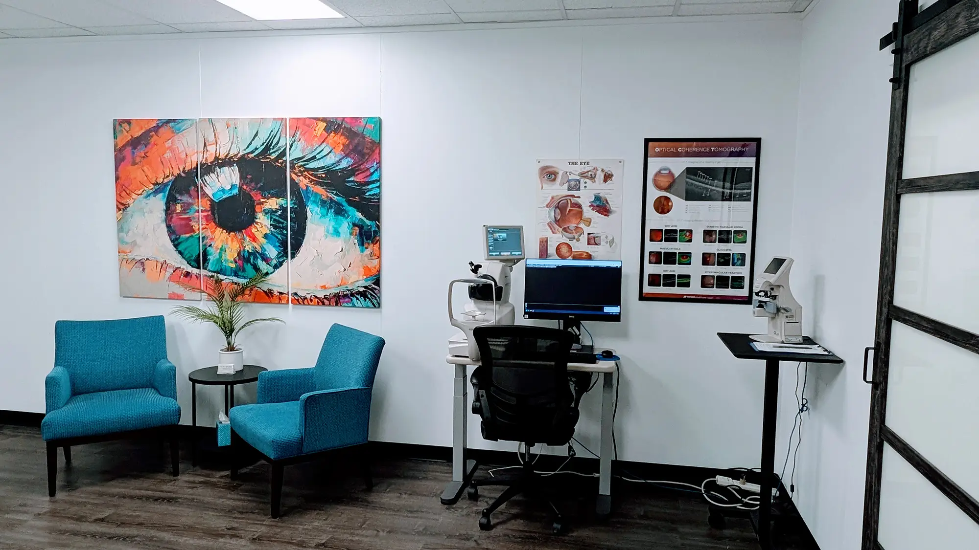 An optometrist's office with a desk, chairs, and artwork on the wall.