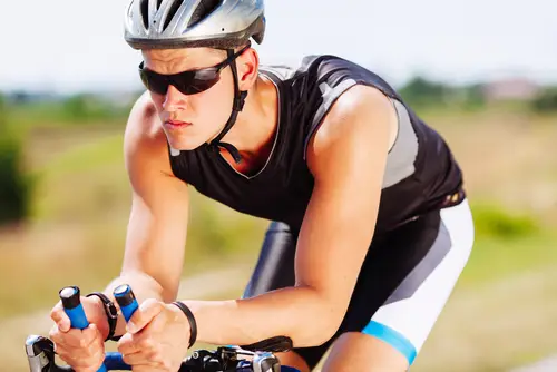 Man wearing helmet riding bike outdoors on a sunny day
