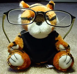 A stuffed tiger with glasses sitting on a carpeted floor