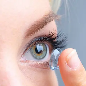 Close up of a woman putting a contact lens into her eye.