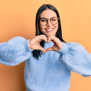 Woman in a blue sweater making a heart shape with her hands