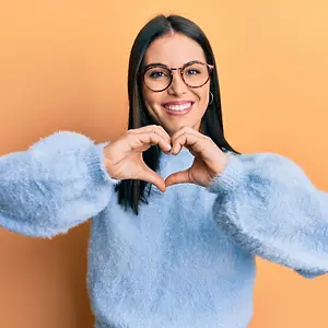 Woman in a blue sweater making a heart shape with her hands