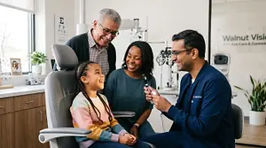 A family, consisting of a young girl, an adult man, a woman, and a doctor, are smiling while sitting in a dentist's chair in a dental clinic.
