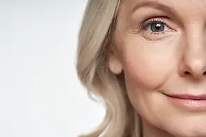 Close-up of a woman's face with blonde hair and wrinkles around the eyes.