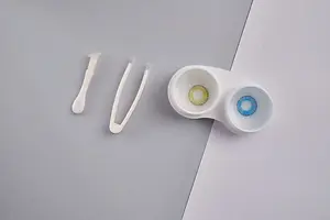 Contact lenses with cleaning solution and tweezers on a gray surface