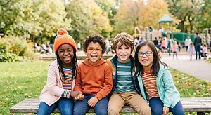 A group of children smiling and posing for a picture in a park