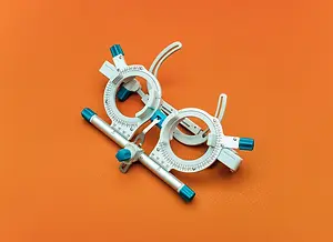 An optometrists phoropter with the lens removed on a bright orange background