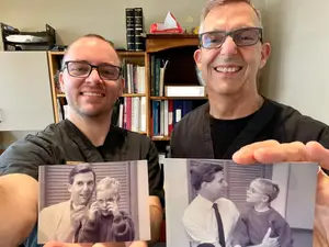 Dr. Jeffrey Allgeier and Dr. Jason Allgeier smiling and both holding up photographs of a man and a young boy