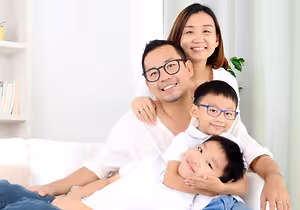 A happy family with two young children sitting on a couch in a living room