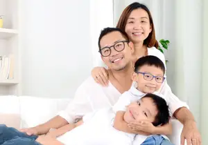 A happy family with two young children sitting on a couch in a living room