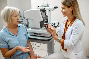 An elderly woman is having her eye examined by a doctor in a clinic.