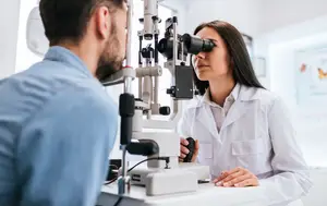 A man is having his eyes examined by a woman doctor in a medical clinic.