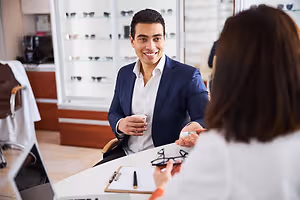 Optician discussing eyeglasses with a smiling customer in a glasses showroom