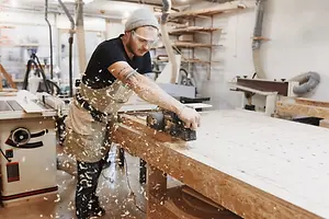 A man working in a workshop with a tool on a wooden table