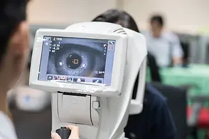 A man using an eye scanning device to examine a patient's eye