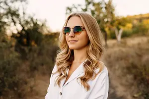 Woman wearing sunglasses standing in a field with a blurred background