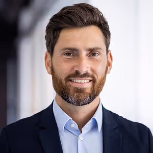Photo of a man in a business suit smiling for the camera