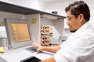 A man is typing on a computer with a monitor in a laboratory setting.