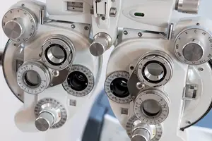 An ophthalmic instrument with adjustable lenses and dials used for examining eyes, positioned on a white background.