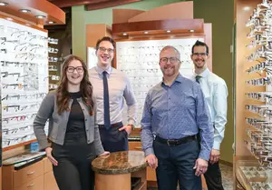 Four people smiling in front of an eyeglasses display
