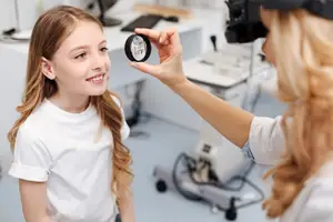 A young girl is having her eyes examined by a female doctor in a clinic.