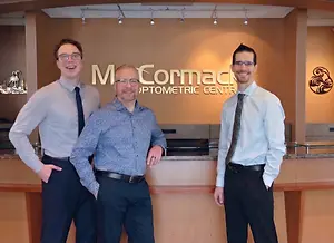 Dr. Joel Baillargeon, Dr. Richard McCormack and Dr. Trevor Horn standing in front of the reception desk at McCormack Optometric Centre