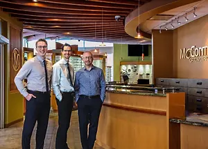Dr. Joel Baillargeon, Dr. Richard McCormack and Dr. Trevor Horn standing in front of the reception desk at McCormack Optometric Centre