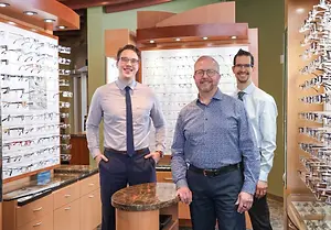 Dr. Joel Baillargeon, Dr. Richard McCormack and Dr. Trevor Horn standing in front of eyeglasses on display