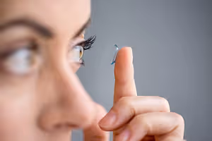 Close up of a woman placing a contact lens in her eye