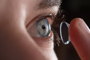 A close-up of a person's eye with a contact lens, the contact lens appears blurry and slightly out of focus.