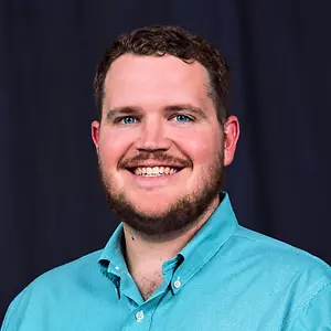 Portrait of a smiling man with a beard wearing a turquoise button-down shirt