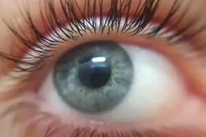 Close-up of a person's eye with gray iris, black pupil, and eyelashes