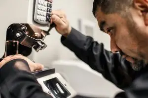 A man in a black shirt is fixing something with a screwdriver in a room with white walls