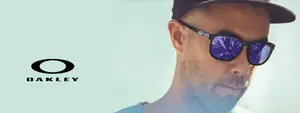 A man with a beard wearing Oakley sunglasses and a cap is looking to the side