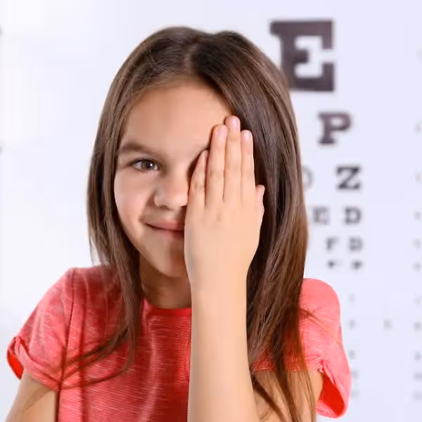 A young girl covering one eye during an eye exam