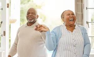 Two people are smiling and laughing in a room with a glass window