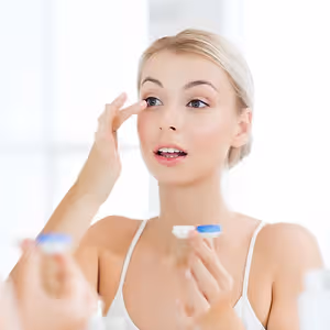 Lady in front of a mirror wearing contact lens