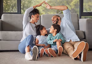 A family sitting on a couch in their living room with one child sitting on the floor