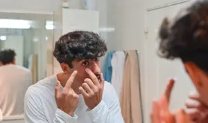 A man putting on scleral lenses in front of a mirror