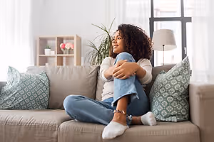 Woman sitting on a couch and smiling while looking to the side