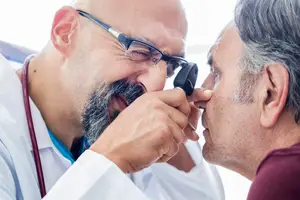 an old man is having his ear checked by a doctor